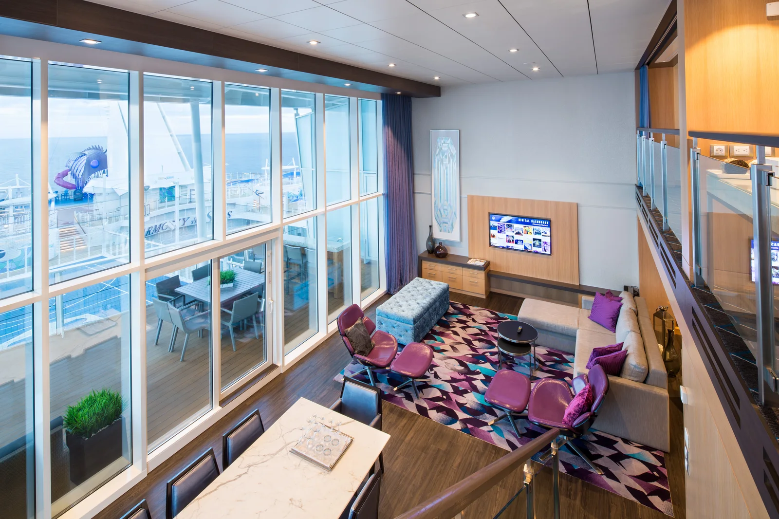Royal Loft Suite two-story living room on Icon of the Seas with floor-to-ceiling views of waterslides and pool decks below